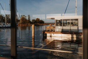 Een boot afgemeerd in een jachthaven met een houten dek en een cabine met glazen wanden.