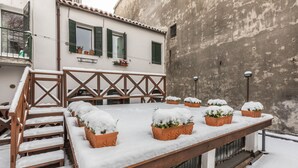 A rooftop terrace with wooden steps and a long wooden platform, covered in snow.