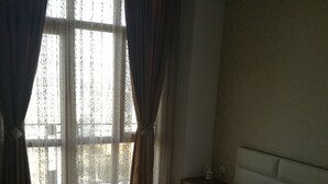 A hotel room with a bed, a nightstand, and a window with curtains. - Saburtalo flat - Comfort created for you! (Tbilsi)