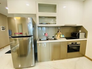 Kitchen features a stainless steel refrigerator, microwave, sink, and small oven, with a window above the sink.