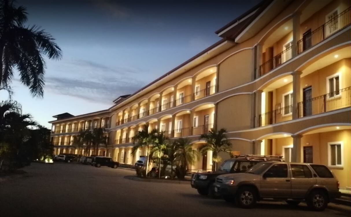 A multi-story hotel with balconies and a parking area.
