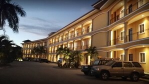Un hotel de varios pisos con balcones y un estacionamiento.