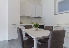 A modern kitchen with white cabinets, a central island with seating, and a window above the sink.