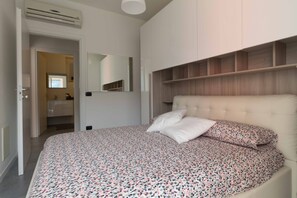 A bedroom with a bed, a mirror, and built-in shelving.