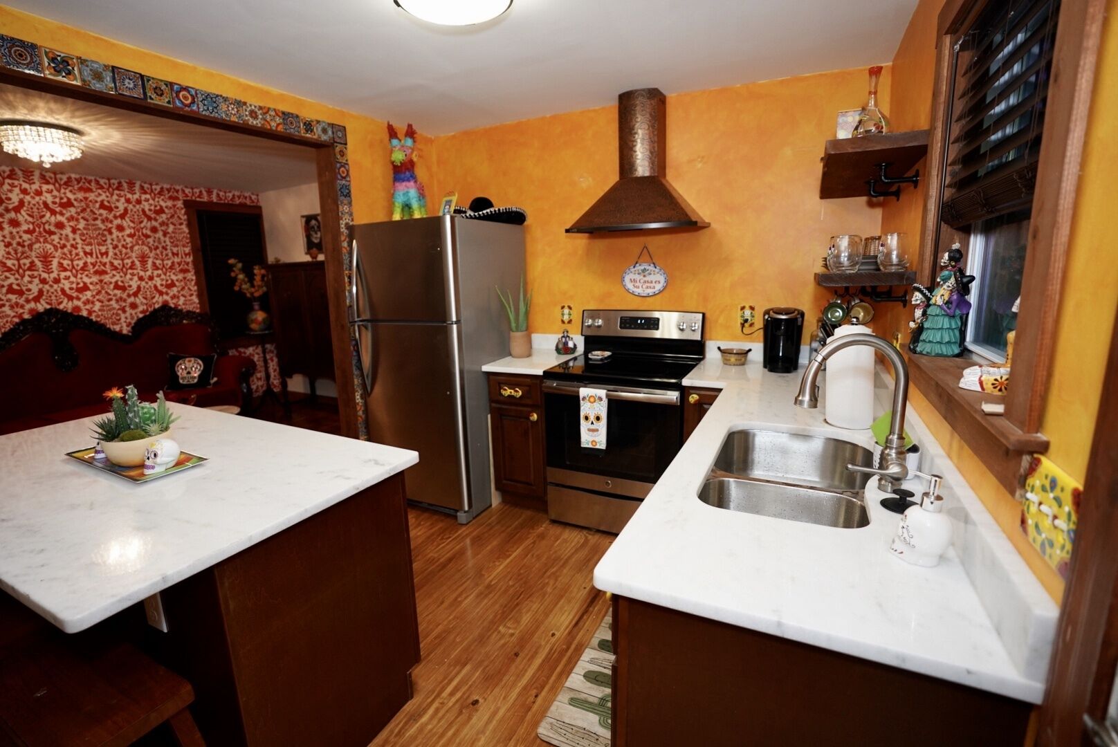 Une cuisine équipée d’un réfrigérateur, d’un four, d’un évier et ornée d’un mur décoratif.