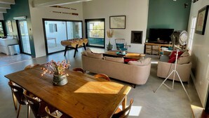 Un salon spacieux avec une table à manger en bois, des canapés, un téléviseur et une cheminée.