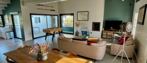 A spacious living room with a wooden dining table, sofas, a TV, and a fireplace.