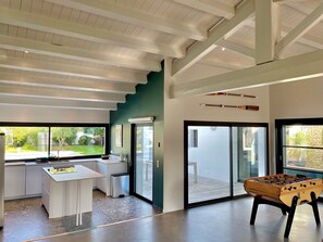 Un intérieur moderne comprenant un espace cuisine, une table à manger et une table de baby-foot.