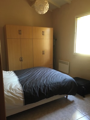 A bedroom with a bed, a wardrobe, a radiator, and a window. - CORSICA - AJACCIO Charming villa with ocean views, 100 meters from the beach (APPIETTO)
