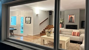A modern living room with a sofa, coffee table, and a fireplace. There is a staircase leading to another level, and a dining area with a table and chairs. - VILLA LOUISE BILBAO, IN A GREEN SETTING, CLOSE TO THE CITY AND BEACHES (Berango)