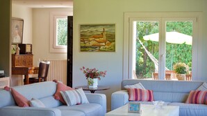 A living room with two sofas, a coffee table, a painting, and a view of greenery outside. - VILLA LOUISE BILBAO, IN A GREEN SETTING, CLOSE TO THE CITY AND BEACHES (Berango)
