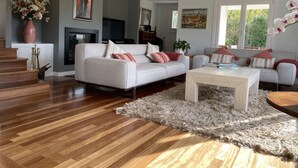 A modern living room with a grey sofa, a white coffee table, and a fluffy rug. There is a fireplace, a TV, and a staircase leading to another room. - VILLA LOUISE BILBAO, IN A GREEN SETTING, CLOSE TO THE CITY AND BEACHES (Berango)