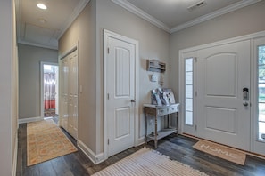 A hallway with two white doors, a small table with magazines, and a 'HOME' mat. - Beautiful Belmont - 4 Bedroom House on Large Fully Fenced Lot (Belmont)