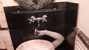 A bathroom with a white pedestal sink, black tiles, and a glass shelf above the sink. - Vecchia Roma House apartment  (Roma)