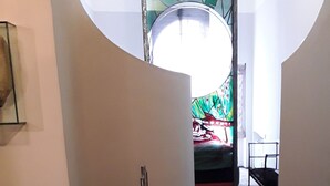 A modern interior with a glass table, a patterned rug, and a staircase leading to a room with a colorful stained glass window. - Vecchia Roma House apartment  (Roma)
