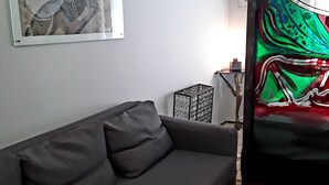 A modern living room with a grey sofa, a framed artwork on the wall, and a colorful abstract painting. - Vecchia Roma House apartment  (Roma)