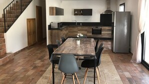 A modern kitchen with a dining area, featuring a wooden staircase, built-in cabinets, a stainless steel refrigerator, and a tiled floor. - Villa located in the heart of Provence with private pool on 3 hectares. (Roquevaire)