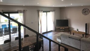 A living room with a sofa, TV, and a dining area with chairs and a table. - Villa located in the heart of Provence with private pool on 3 hectares. (Roquevaire)