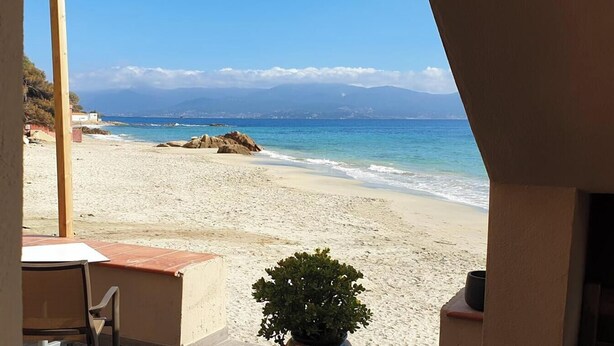 Une chambre avec vue sur la plage, comprenant une table et une chaise, une plante en pot, et offrant un panorama sur l’océan et les montagnes.