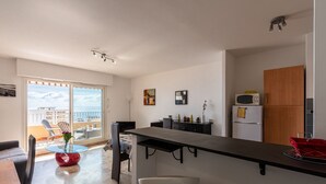 Une cuisine moderne avec une table à manger au plateau en verre, un évier blanc et un meuble en bois.