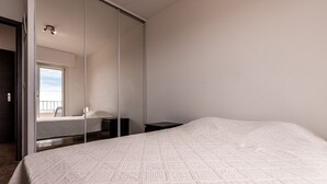 Une chambre à coucher avec un grand lit, une table de chevet, un miroir et une fenêtre donnant sur un beau paysage.