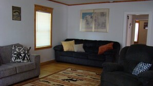 A living room with a grey sofa, a dark armchair, and a patterned rug. - Ft Gibson Lake OK near Sequoyah State Park (Hulbert)