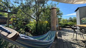 A hammock on a wooden deck with a pergola overhead, surrounded by lush greenery and a clear blue sky. - Holiday Loft AUGUST’S TREASURE CHEST (Marienberg)