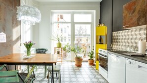 A modern kitchen with a yellow shelf, a stove, and a dining area with a table and chairs. - Holiday Loft AUGUST’S TREASURE CHEST (Marienberg)