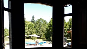 A room with a large window overlooking a pool and outdoor seating area.
