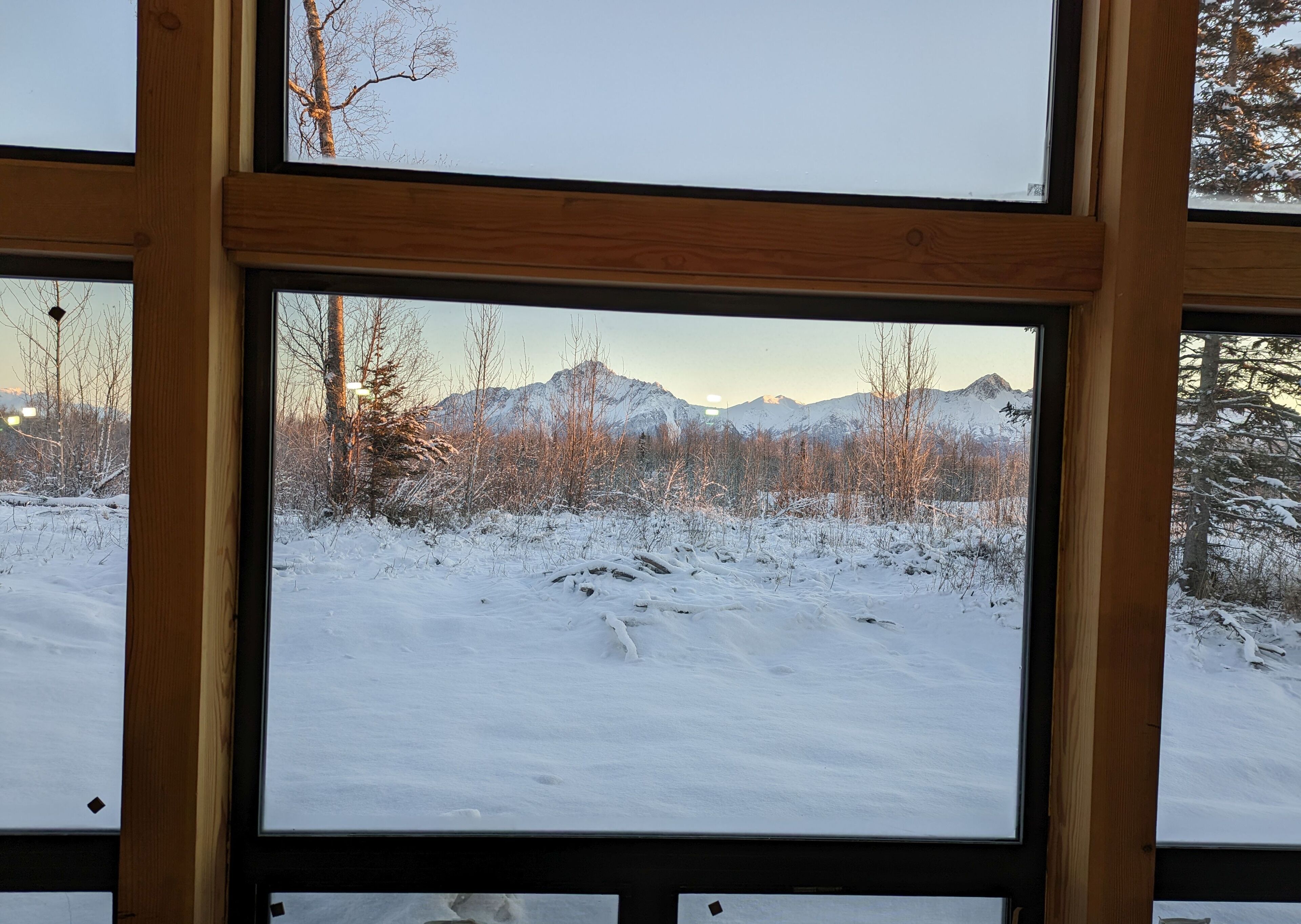 A snowy landscape through a window with a wooden frame.