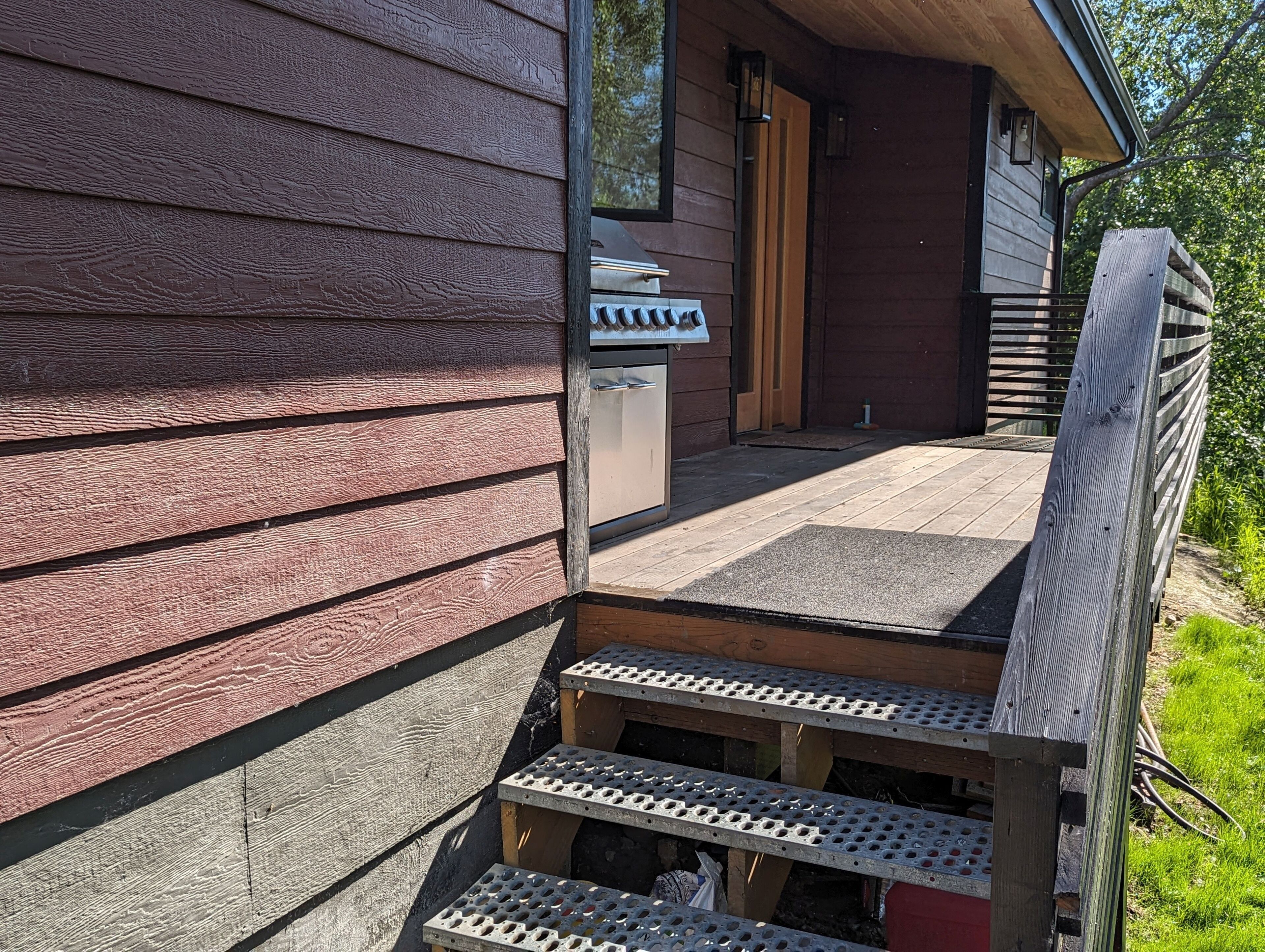 A wooden exterior with a metal staircase leading to a covered porch.