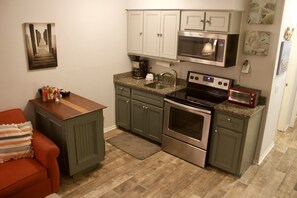 A compact kitchen with a built-in oven, microwave, and a small countertop with a toaster.