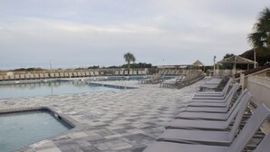 Une piscine avec des chaises longues et une terrasse carrelée.