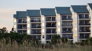 Un hôtel moderne à plusieurs étages, doté de balcons, de grandes fenêtres et d’un toit plat.