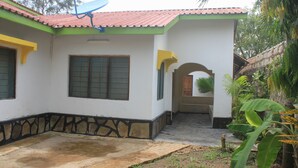 A house with a tiled roof, a satellite dish, and a small garden area with plants. - Maui Palm house, Ukunda, 4 bedroom  secure compound, 10 minutes  to the beach. (Ukunda)