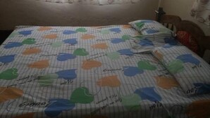 A bed with a striped bedspread featuring colorful abstract shapes and some text. - Maui Palm house, Ukunda, 4 bedroom  secure compound, 10 minutes  to the beach. (Ukunda)