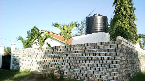 A brick wall with a water tank on top, surrounded by greenery. - Maui Palm house, Ukunda, 4 bedroom  secure compound, 10 minutes  to the beach. (Ukunda)