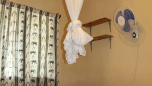 A bedroom with a bed, a hanging mosquito net, a wall fan, and a window with patterned curtains. - Maui Palm house, Ukunda, 4 bedroom  secure compound, 10 minutes  to the beach. (Ukunda)