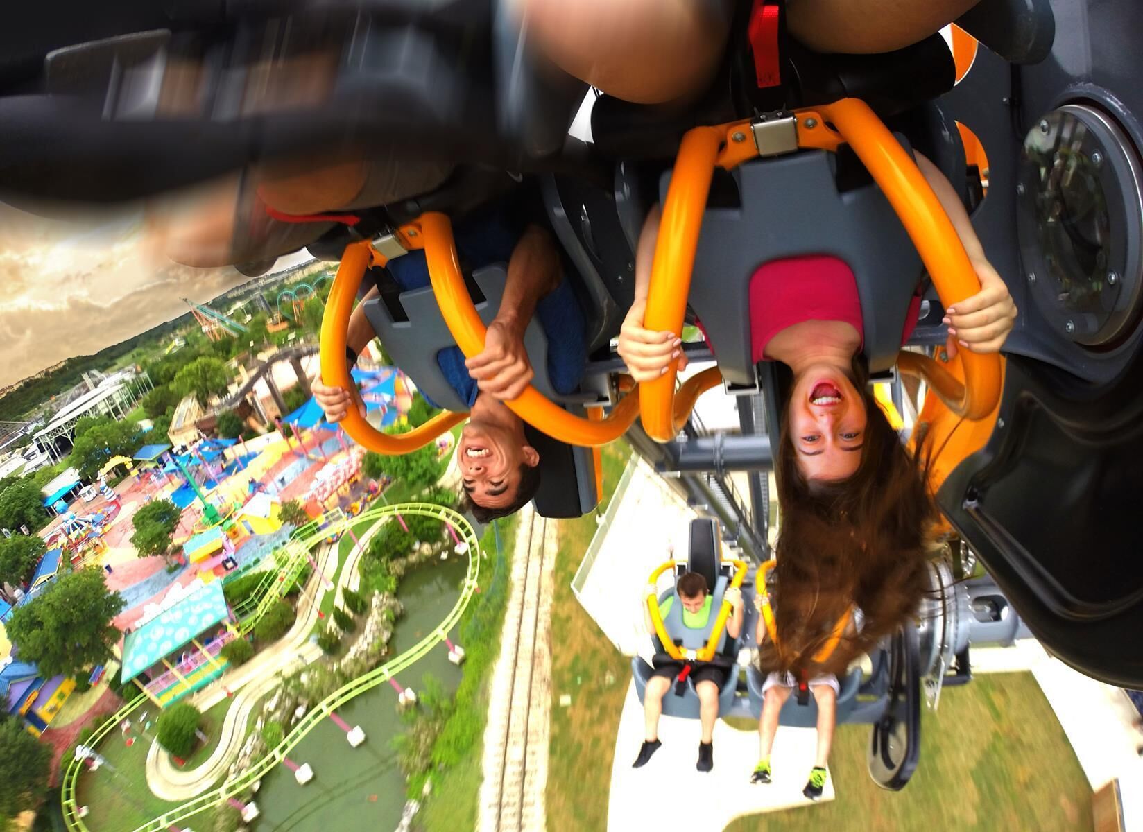 Blick von einer Achterbahn, inklusive der Gleise und des umliegenden Freizeitparkbereichs.
