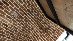 Un muro de ladrillo con una viga de madera y un enchufe.