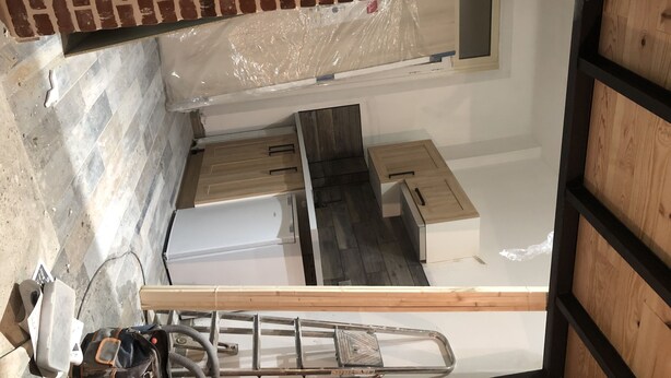 Una habitación con techo de ladrillo, suelo de madera y pared blanca.