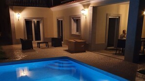 A swimming pool with a blue tint, surrounded by a covered patio area with seating and tables. - New house 100 metres from the beach in LAGOA DE ALBUFEIRA (LAGOA DE ALBUFEIRA)