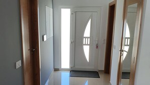A hallway with a polished floor, a door with a unique cut-out design, and a light fixture on the ceiling. - New house 100 metres from the beach in LAGOA DE ALBUFEIRA (LAGOA DE ALBUFEIRA)