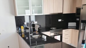 A modern kitchen with a black countertop, stainless steel appliances, and light wood cabinets. - New house 100 metres from the beach in LAGOA DE ALBUFEIRA (LAGOA DE ALBUFEIRA)