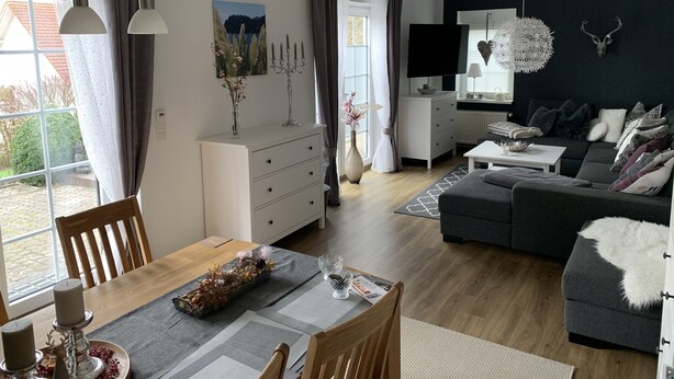 A modern living room with a dining area, featuring a sofa, a TV, and a fireplace. - Apartment in a beautiful quiet location (Hann. Münden)