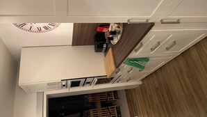A modern kitchen with white cabinets, a wooden countertop, and a built-in clock. - Apartment in a beautiful quiet location (Hann. Münden)