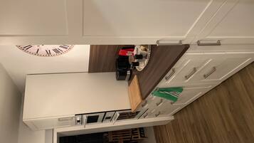 Eine moderne Küche mit weißen Schränken, einer Holz Arbeitsplatte und einer eingebauten Uhr.