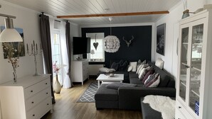 A modern living room with a grey sofa, white cabinet, and a dining area with a table and chairs. - Apartment in a beautiful quiet location (Hann. Münden)