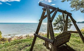 Et træsvingesæt med udsigt over en sø, hvor vandet og landskabet i det fjerne kan ses klart.
