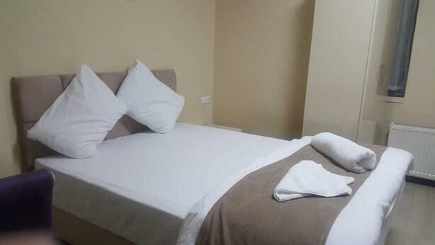 Una habitación de hotel con una cama, almohadas, una colcha y una silla.